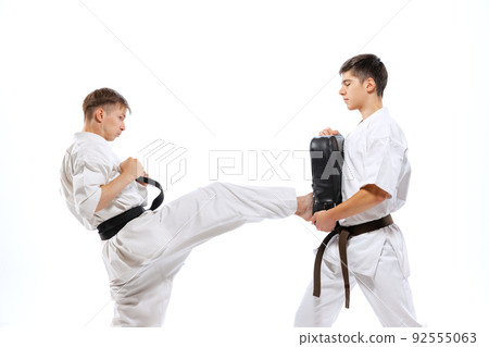 Two athletes, karate-do fighters in doboks practicing karate isolated on white background. Concept of sport, education, skills, martial arts, healthy lifestyle 92555063