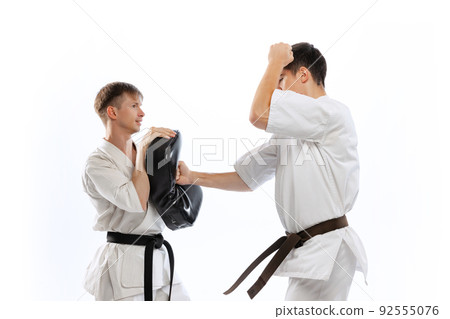 Two athletes, karate-do fighters in doboks practicing karate isolated on white background. Concept of sport, education, skills, martial arts, healthy lifestyle 92555076
