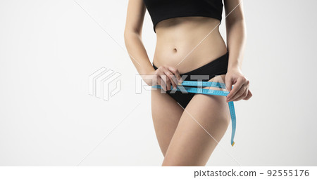 Front view of woman girl taking measurements of her body on white background with a measuring tape. Front view of woman girl taking measurements of her body on white background with a measuring tape. 92555176