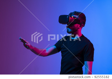 Teen male student use vr glasses and looks at empty copy space. Virtual gadgets for entertainment, work, free time and study. Virtual reality metaverse technology concept. 92555182
