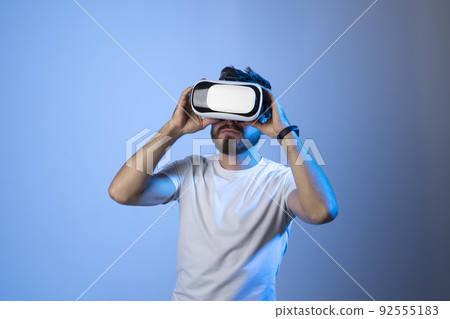 Closeup portrait of a man wearing VR goggles, working over virtual project, enjoying new reality, playing video game. Technology, innovation gadgets. 92555183