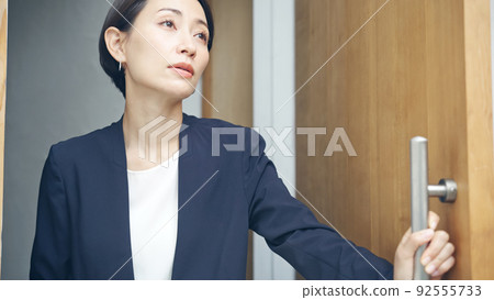 A woman who opens the door with a melancholy look A woman who opens the door with a melancholy look 92555733