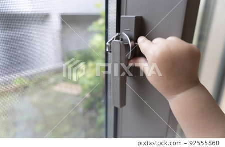 Baby's hand trying to remove the windowpane crescent 92555860