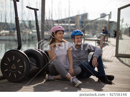young couple guy and girl are walking on the segway along the board paved promenade in the port of a European city 92556148
