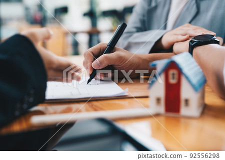 Business woman and young couple signing agreement for buying house. Bank manager and real estate concept. Business woman and young couple signing agreement for buying house. Bank manager and real estate concept. 92556298