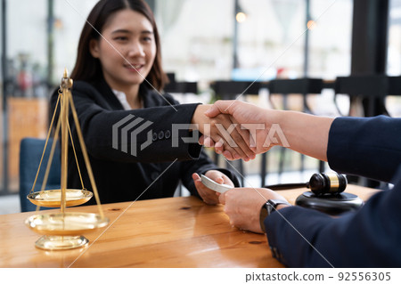The Lawyer is currently shaking hands with the client about the success in resolving the case. The Lawyer is currently shaking hands with the client about the success in resolving the case. 92556305