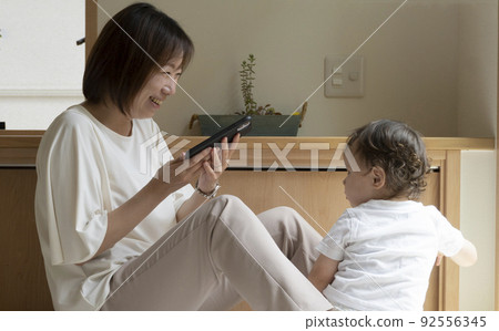 Mother showing the screen of the smartphone to the child Mother showing the screen of the smartphone to the child 92556345