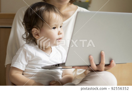 Half boy looking at a PC with his mother 92556352