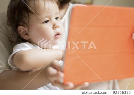 Half-boy enjoying watching a tablet PC with his mother 92556353