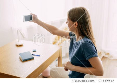 A charming student communicates with friends via video link, discusses a school or university project. Online communications, modern technologies, online education 92556642