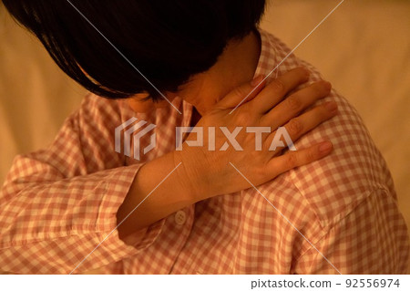 Middle woman suffering from stiff shoulders in pajamas 92556974