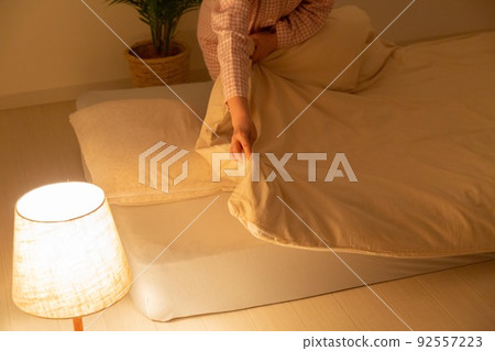 A middle-aged woman wearing pajamas and preparing a futon A middle-aged woman wearing pajamas and preparing a futon 92557223