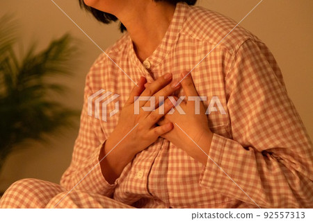 Middle-aged woman in pajamas suffering from chest pain 92557313