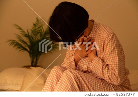 Middle-aged woman in pajamas suffering from chest pain Middle-aged woman in pajamas suffering from chest pain 92557377