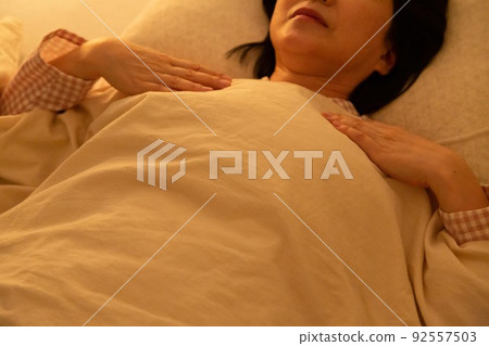 Middle woman wearing pajamas and sleeping on a futon Middle woman wearing pajamas and sleeping on a futon 92557503