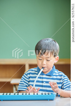 小學男孩在教室裡彈鍵盤口琴 小學男孩在教室裡彈鍵盤口琴 92557611