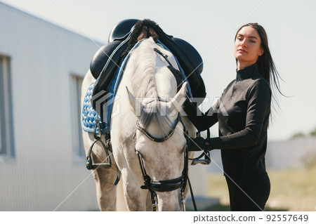 Live portrait of young beautiful woman with her horse in summer warm day, outdoors. Lifestyle mood. Concept of nature, animal, care, sport 92557649