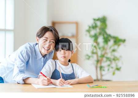 Parents and children (mother and child) doing homework together in the living room Parents and children (mother and child) doing homework together in the living room 92558896