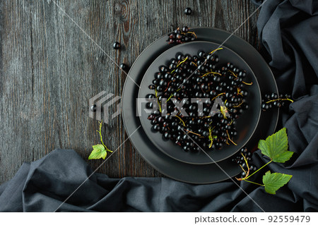 Black currant with leaves on a old wooden table. Black currant with leaves on a old wooden table. 92559479