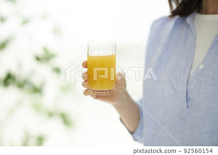 Hands of a middle-aged woman with orange juice 92560154