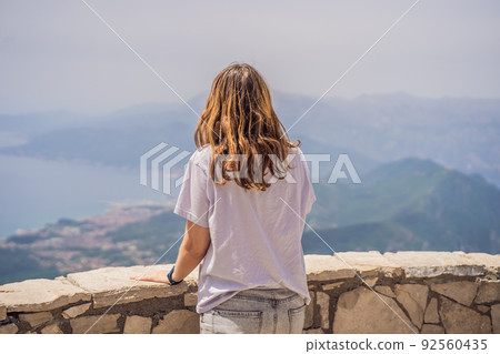 Woman tourist enjoys the view of Kotor. Montenegro. Bay of Kotor, Gulf of Kotor, Boka Kotorska and walled old city. Travel to Montenegro concept. Fortifications of Kotor is on UNESCO World Heritage 92560435