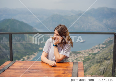 Woman tourist enjoys the view of Kotor. Montenegro. Bay of Kotor, Gulf of Kotor, Boka Kotorska and walled old city. Travel to Montenegro concept. Fortifications of Kotor is on UNESCO World Heritage 92560440