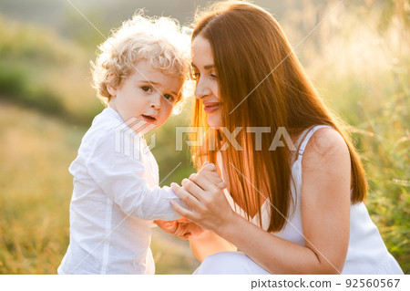 Happy woman holding her son by the hand in nature 92560567