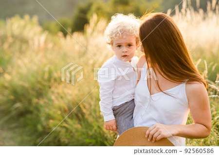 Woman with her son in her arms is walking in nature Woman with her son in her arms is walking in nature 92560586