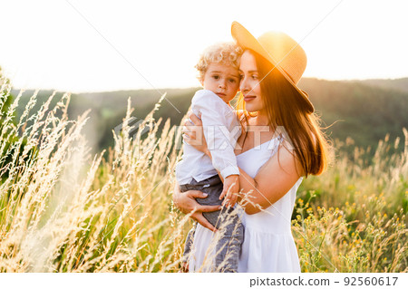 Mother hugs her son while walking in nature at sunset 92560617