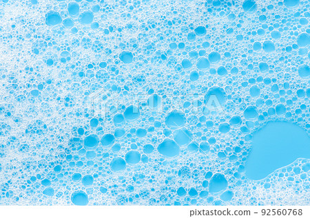 Texture of white foam on a blue background. Cleansing mousse for the face or bath foam or washing powder. Closeup 92560768