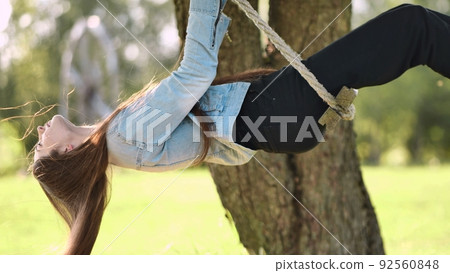 Young beautiful long-haired girl on a rope swing. Young beautiful long-haired girl on a rope swing. 92560848