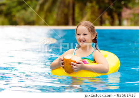 Child with coconut drink. Kids in swimming pool. 92561413