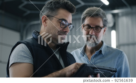 Mechanic swiping on tablet near a client 92561639
