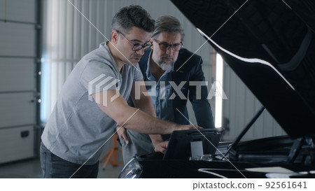Mechanic checking car engine using tablet 92561641