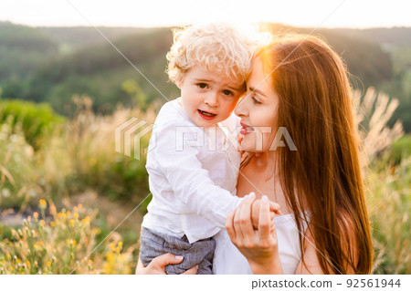 Loving mother hugs her son while walking in nature at sunset 92561944