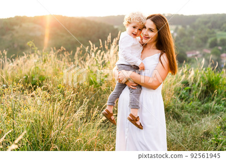 Pretty woman holding her son in arms. Happy family in nature. Pretty woman holding her son in arms. Happy family in nature. 92561945