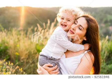 Happy mother hugging her son at sunset 92561946