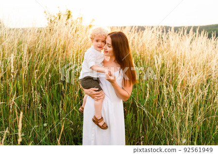 Loving mother with her son in arms in the middle of the field Loving mother with her son in arms in the middle of the field 92561949