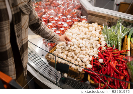 Woman chooses champignons in the vegetable section of the supermarket 92561975