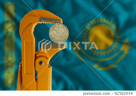 50 Kazakhstani tenge held in an orange plumber wrench on the background of the flag of Kazakhstan 92562034