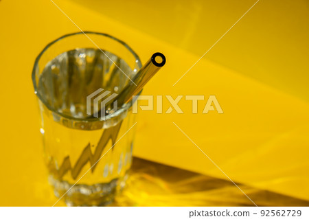 Reusable glass Straws in Glass with water on yellow background Eco-Friendly Drinking Straw Set with cleaning brush. Zero waste, plastic free concept 92562729