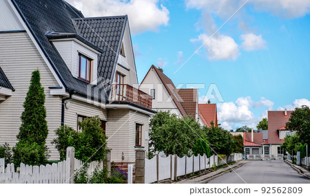 A private house of two floors with triangular roof and an area near the house against a blue sky A private house of two floors with triangular roof and an area near the house against a blue sky 92562809