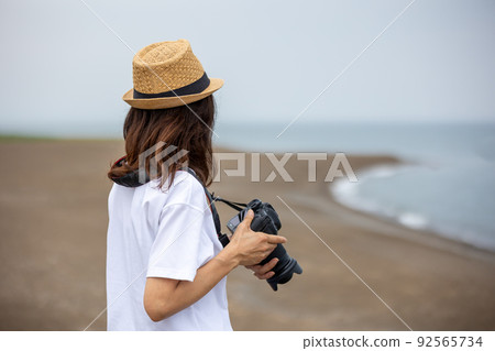 A woman shooting a seaside landscape 92565734