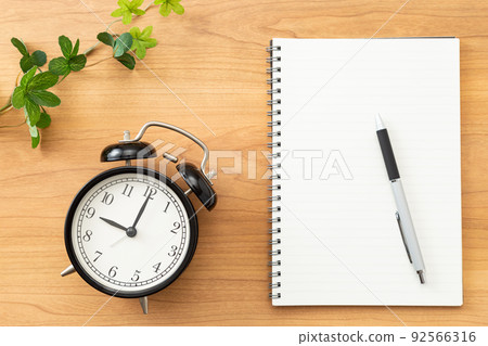 Clock and notebook placed on the desk Clock and notebook placed on the desk 92566316