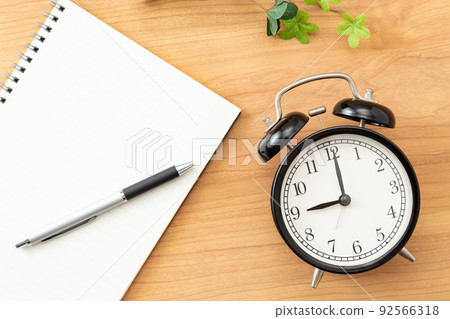 Clock and notebook placed on the desk Clock and notebook placed on the desk 92566318