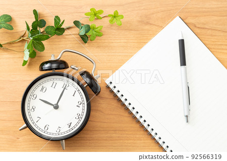 Clock and notebook placed on the desk 92566319