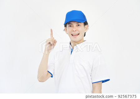 A man in a cap and polo shirt uniform pointing to the left white background 92567375