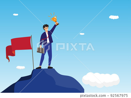 Businessman holding up a gold trophy cup with success flag on top of mountain 92567975