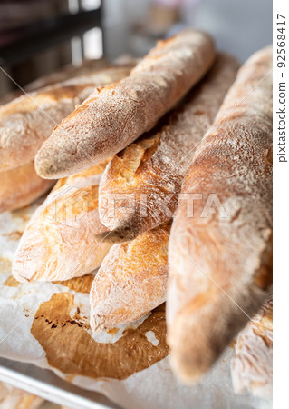 Finished French bread in the bakery on the racks. Baguettes, rustic bread. Vertical photo. Finished French bread in the bakery on the racks. Baguettes, rustic bread. Vertical photo. 92568417