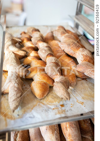 Finished French bread in the bakery on the racks. Baguettes, rustic bread. Vertical photo. Finished French bread in the bakery on the racks. Baguettes, rustic bread. Vertical photo. 92568419